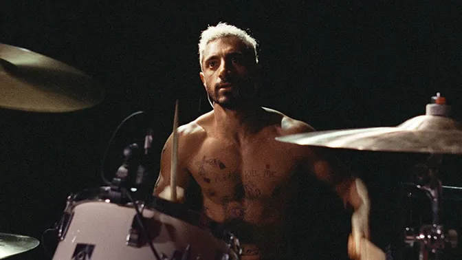 Riz Ahmed at a drum kit